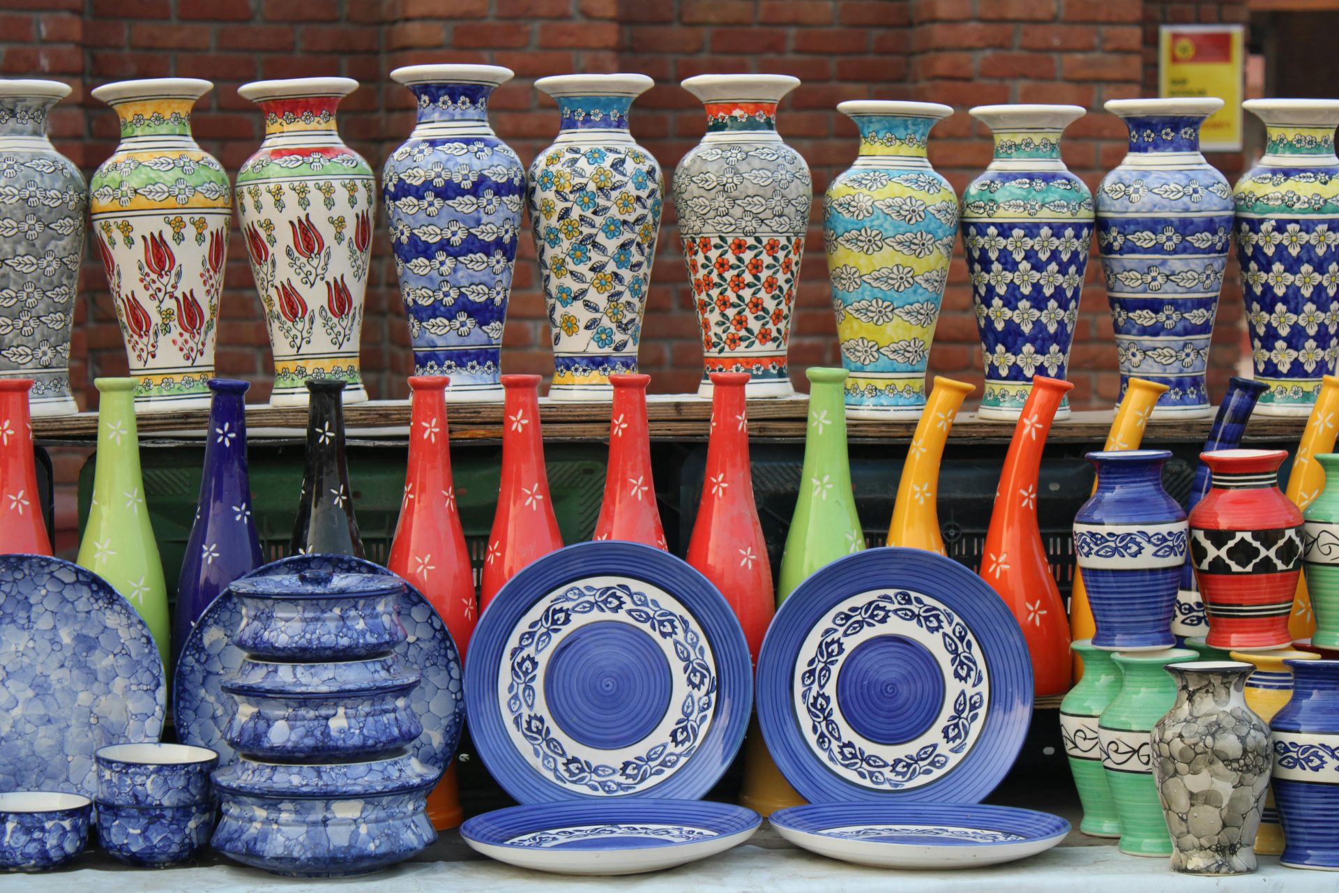 Vibrant collection of ceramic vases and plates at an outdoor market showcasing intricate patterns and colors.