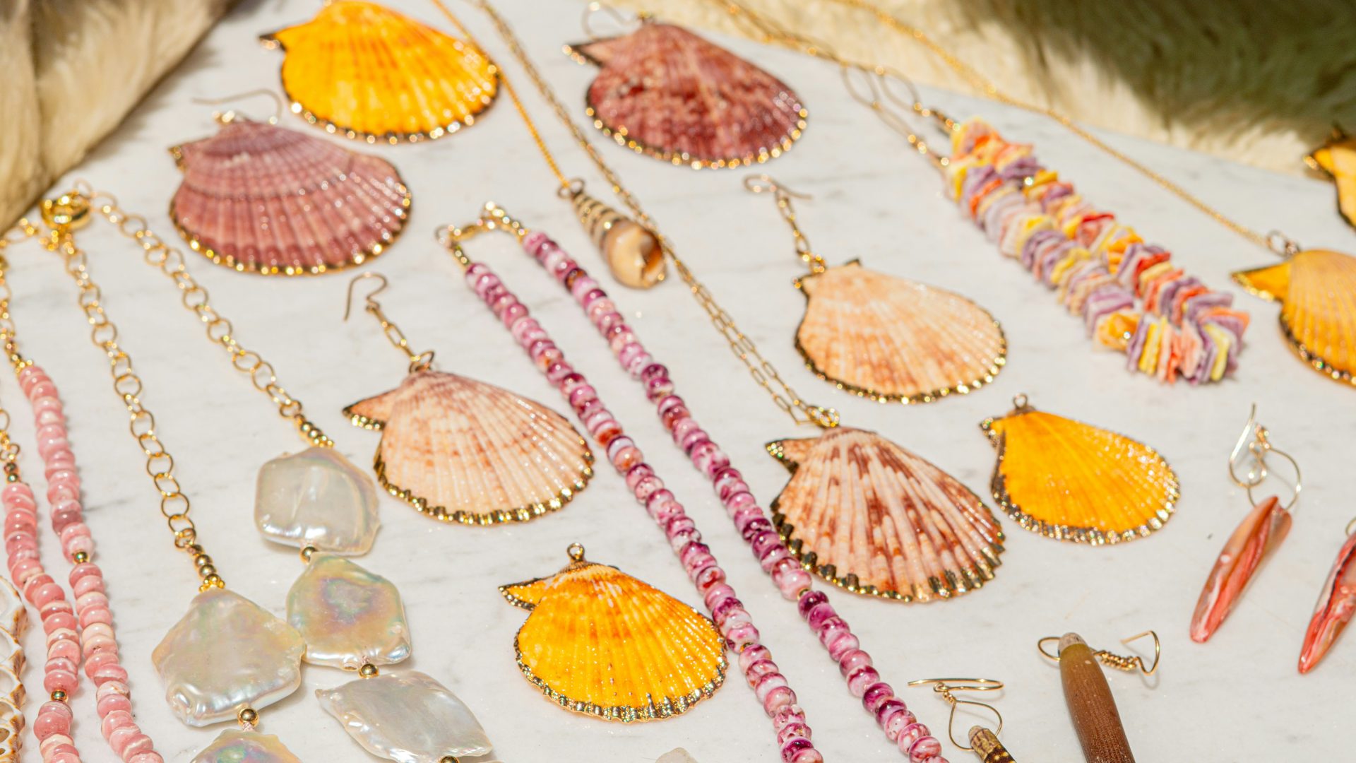 Seashell jewelry pieces are arranged on a white surface.